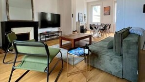A living room with a sofa, a television, a fireplace, and a dining area in the background. - Le Triplex Grand Appart Vue Théâtre  (Cherbourg-en-Cotentin)