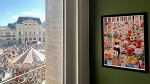 A view of a building with a large crowd, a balcony, and a framed floral artwork on the wall. - Le Triplex Grand Appart Vue Théâtre  (Cherbourg-en-Cotentin)