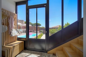 A room with a large sliding glass door leading to a pool area, a wooden bench, and a staircase. - Villa Pont Saint-Victor with Private Pool, 4 Bedrooms (Cannes)