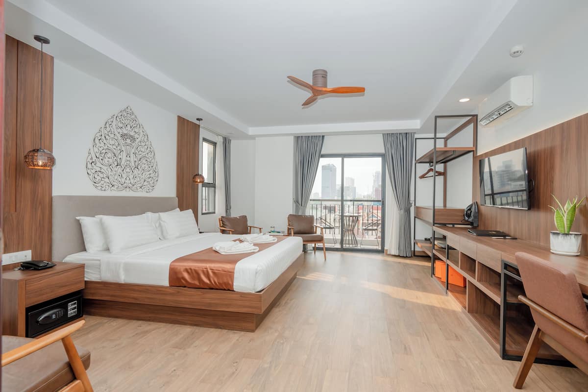 Una habitación de hotel moderna con una cama grande, un escritorio, una silla, un televisor y un balcón con vista a la ciudad.