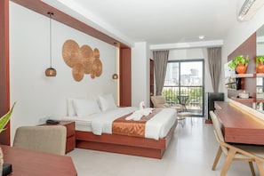 A modern hotel room with a bed, bedside table, and a dining area with a wooden table and chairs.
