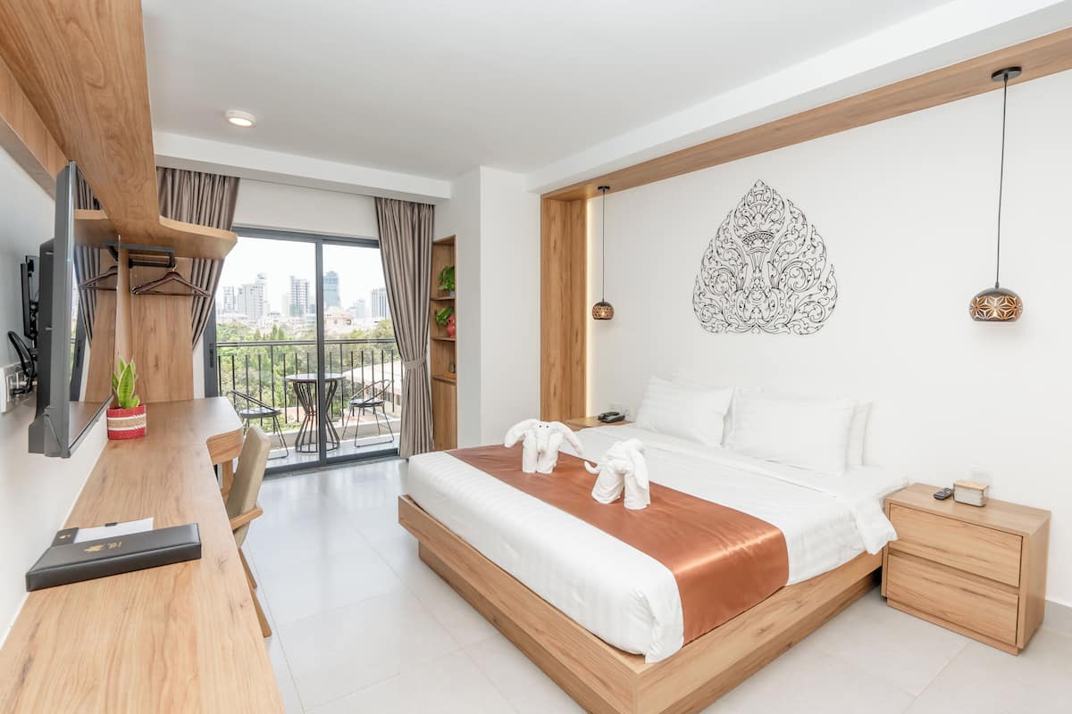 Una habitación de hotel moderna con una cama grande, un escritorio de madera, un balcón con vistas a la ciudad y un elemento decorativo en la pared.