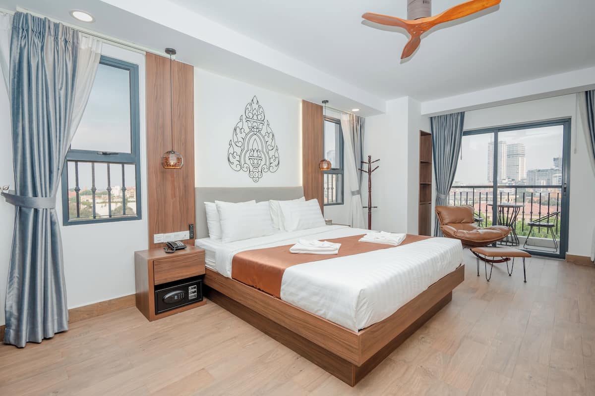 Habitación de hotel con una cama grande, un escritorio, una silla y vistas a la ciudad.