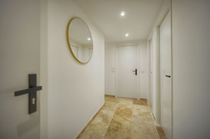 A hallway with a mirror, a door with a cross-shaped handle, and a tiled floor. - TOWNHOUSE 3 Bedroom Deluxe Apartment (Cannes)