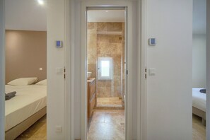 A hotel room with a bed, a bathroom with a shower, and a small window. - 1539891004 TOWNHOUSE Deluxe 3-Bedroom Apartment   (Cannes)