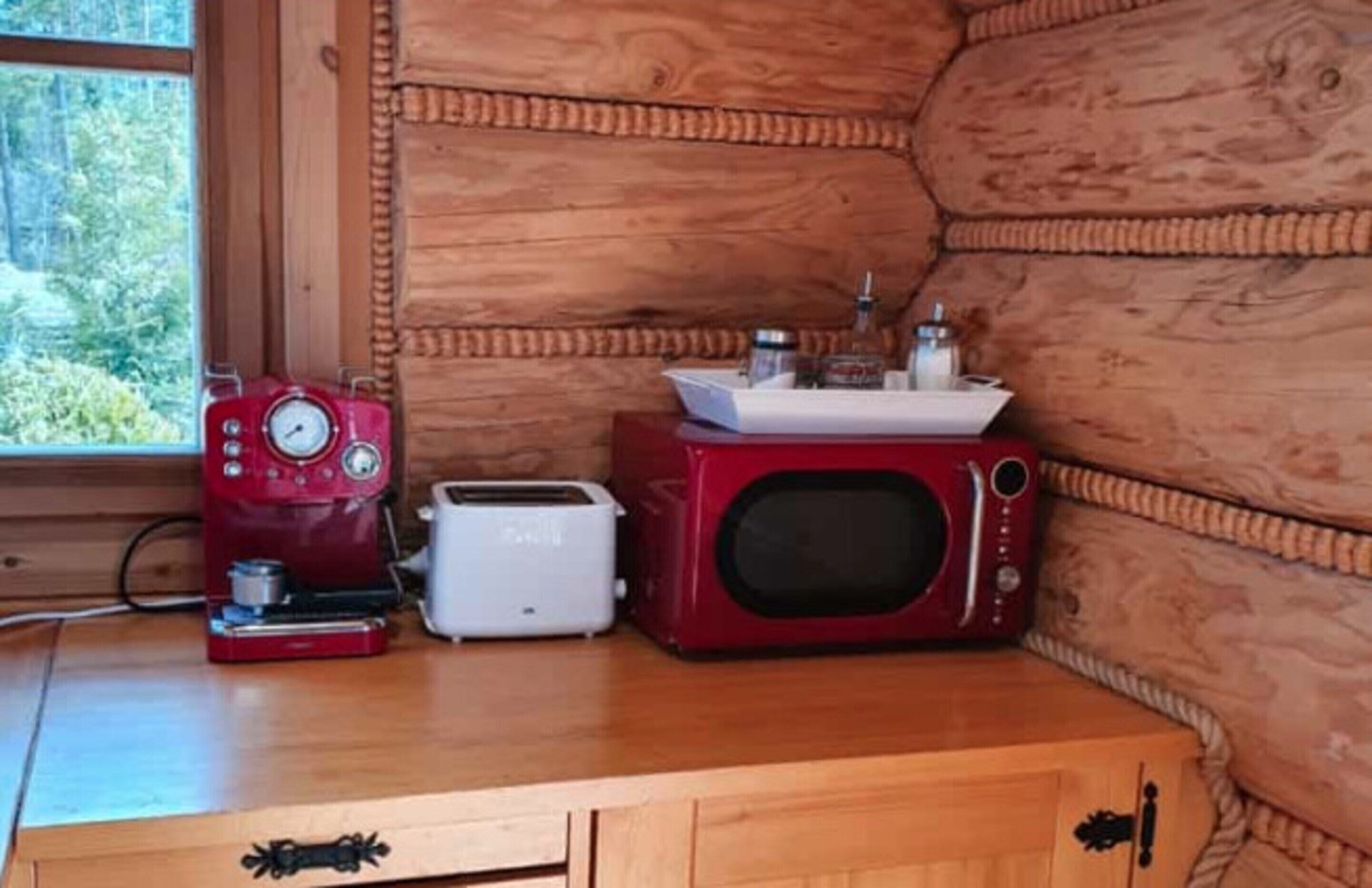Cocina compacta con cafetera, tostadora y microondas sobre una encimera de madera.