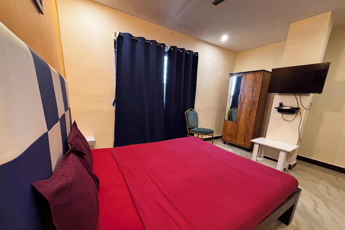 Una habitación de hotel con cama, una silla, armario y televisión.
