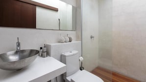 A modern bathroom with a large vessel sink, a toilet, and a glass-enclosed shower. - Villa Koru (Surat Thani)