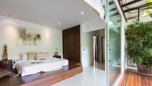A modern bedroom with a bed, bedside tables, a large window, and a potted plant. - Villa Koru (Surat Thani)