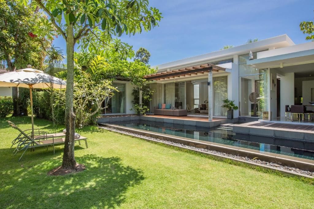 Uma casa moderna com piscina, área de estar externa e jardim bem cuidado.