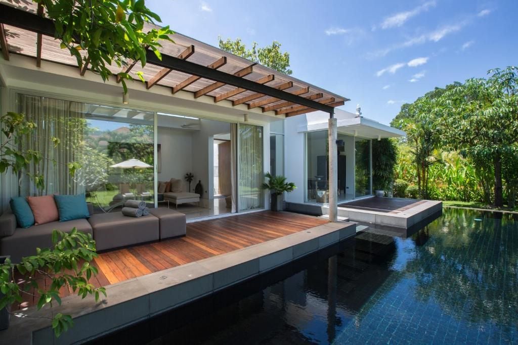 Uma casa moderna com piscina, deck de madeira e área de estar coberta ao ar livre.