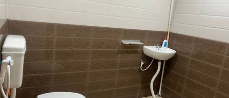 Un baño con inodoro, lavabo y zona de ducha.