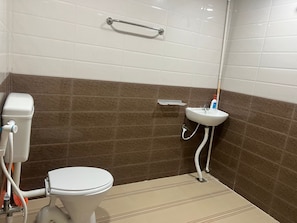 A bathroom with a toilet, a sink, and a shower area. - Aerodon resort (Tirupporur)