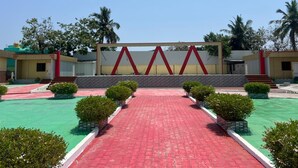 A courtyard with a red brick pathway, a geometric wall structure, and greenery. - Aerodon resort (Tirupporur)