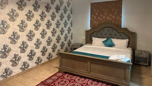 A bedroom with a bed, a chandelier, an air conditioner, and patterned wallpaper. - Aerodon resort (Tirupporur)