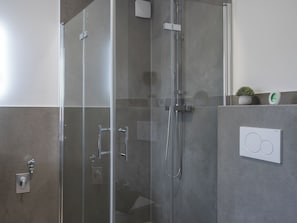 A modern bathroom with a glass-enclosed shower, a wall-mounted control panel, and a small potted plant on the wall. - Ferienwelt Wittenberge - Elbe Apartment (wittenberge)