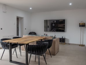 A modern dining area with a wooden table and black upholstered chairs, a sofa, a small cabinet, and a floor lamp. - Modern apartment with 2 bedrooms for up to 6 guests (wittenberge)