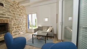 Un salon avec un mur en pierre, une cheminée, un canapé, une table basse et une porte-fenêtre coulissante.