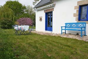 A white building with a blue door and window, a bench, and a table with chairs outside. - 8 min. walk from the beach - Charming house (10 p.) - in a green setting (Plouhinec)