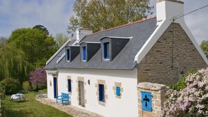 Une maison blanche aux murs de pierre, aux portes bleues et au toit en pente.