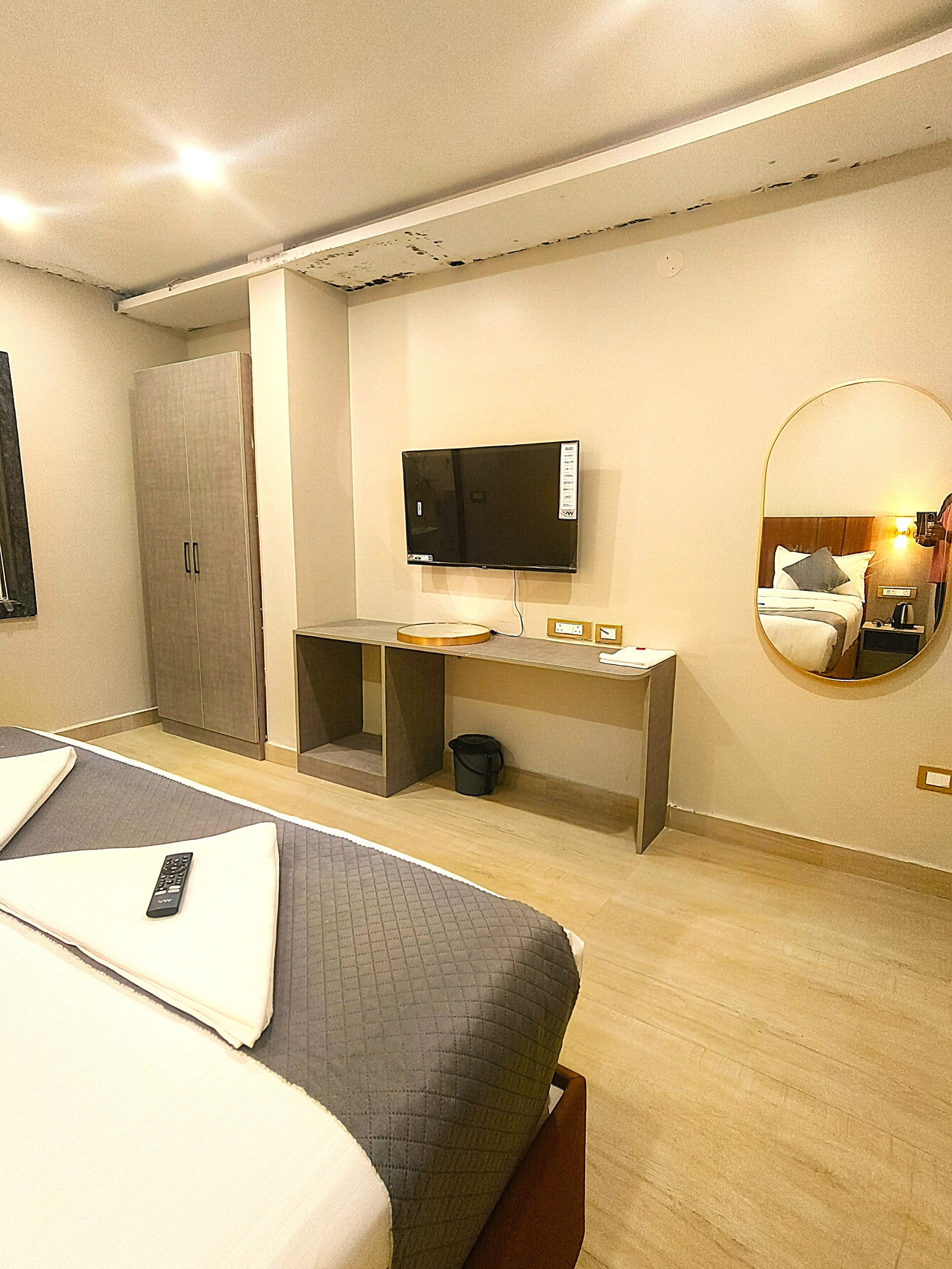 A hotel room with a bed, a desk, a television, and a mirror.