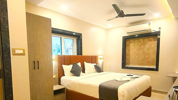 Une chambre d’hôtel moderne équipée d’un lit, d’une table de chevet, d’une armoire et d’un ventilateur de plafond.