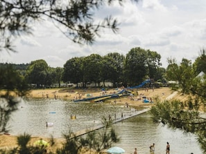 Um parque aquático com praia de areia, escorrega d'água e lago.