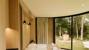 A modern bedroom with a large bed, wooden paneling, and a view of the outdoors. - Holiday Home in Wilsum With Hottub (Wilsum)