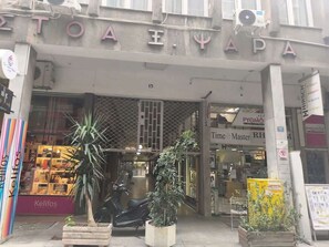 A storefront with a sign that reads 'TOA EYA' and a shop named 'Time Master RH' inside. - Modern Studio l Worn Bldg Entrance (Athina)