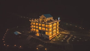 Un edificio de varios pisos con balcones, techo plano y una estructura pequeña adyacente.