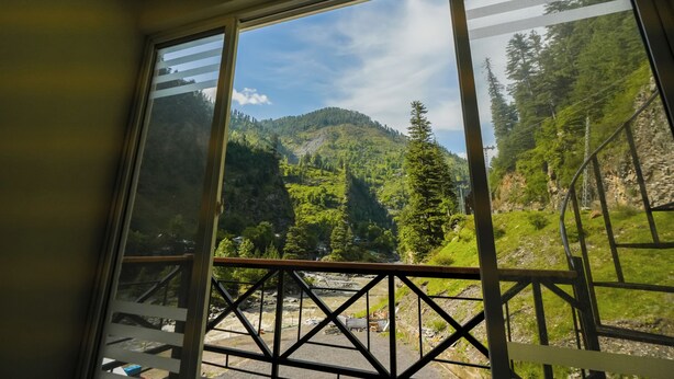A room with a large window overlooking a mountainous landscape. - Hotel One Riverside Kaghan (Balakot)