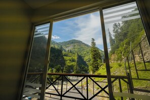 A room with a large window overlooking a mountainous landscape.