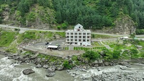 A multi-story hotel with a central courtyard, located near a river and surrounded by greenery. - Hotel One Riverside Kaghan (Balakot)