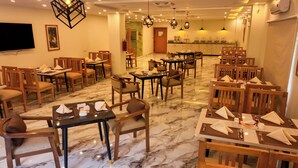 A restaurant with marble flooring, wooden tables and chairs, and pendant lighting. - Hotel One Riverside Kaghan (Balakot)