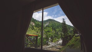 A room with a large window overlooking a mountainous landscape with a river. - Hotel One Riverside Kaghan (Balakot)