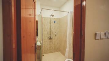 Baño con ducha, inodoro y puertas de madera.