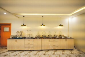 Une cuisine dotée d’un sol en marbre, de meubles de rangement en bois et de trois luminaires suspendus.