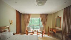 A hotel room with a bed, two chairs, a desk, a mirror, and a window with curtains. - Hotel One Riverside Kaghan (Balakot)