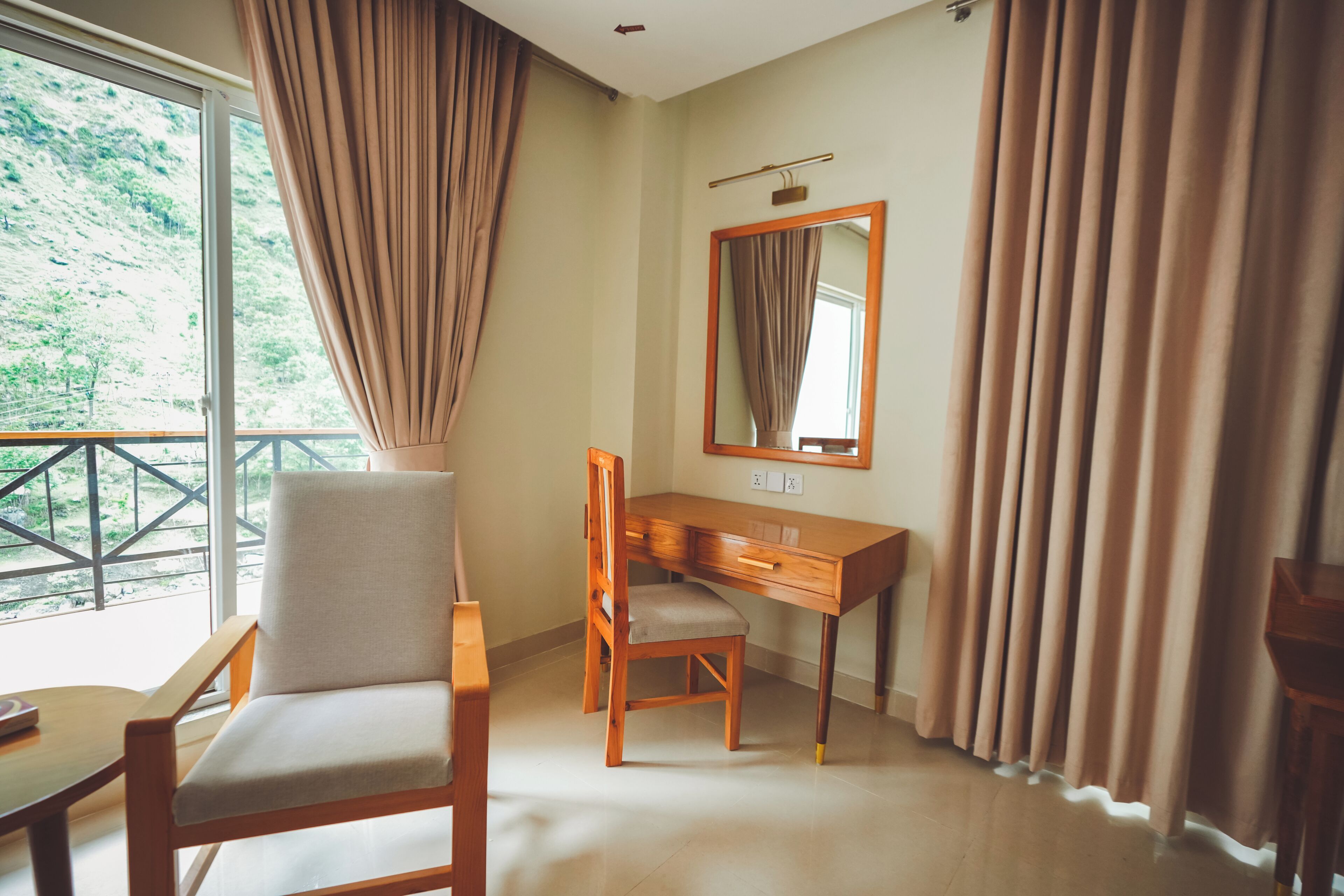 A room with a wooden desk, chair, and a large mirror.