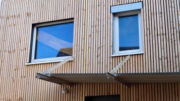 Ein Gebäude mit senkrechten Holzverkleidungen und zwei Fenstern mit weißen Rahmen.