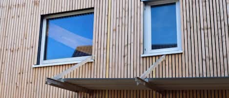 Ein Gebäude mit senkrechten Holzverkleidungen und zwei Fenstern mit weißen Rahmen.