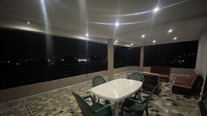 A balcony with a table and chairs, a view of the city at night, and a patterned floor. - Apartment with 360-degree view (Antananarivo)