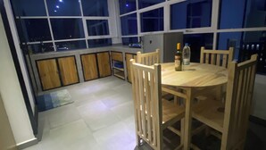 A modern kitchen with a dining area, large windows, and a view of the night sky. - Apartment with 360-degree view (Antananarivo)