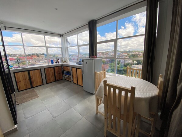 Una cocina con ventanas amplias, una mesa de comedor y un refrigerador.