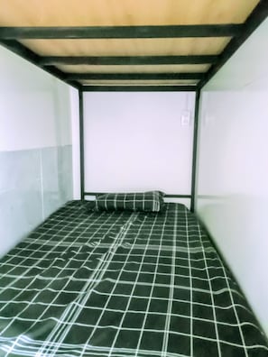 A bunk bed with a checkered bedspread and a pillow. - WeDiscover Da Nang CoLiving & CoWorking (Ngu Hanh Son)