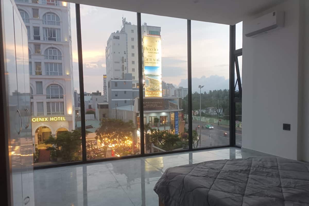 Habitación de hotel moderna con un ventanal grande, una cama y vistas a la ciudad.
