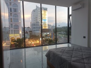 Habitación de hotel moderna con un ventanal grande, una cama y vistas a la ciudad.