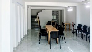 Ein geräumiger Raum mit einem langen Holztisch, Stühlen, einer Treppe und einem Fliesenboden.