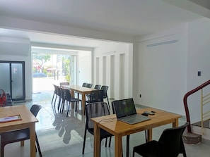 Un interior moderno con una mesa de madera, sillas negras, una computadora portátil y un abanico rojo.
