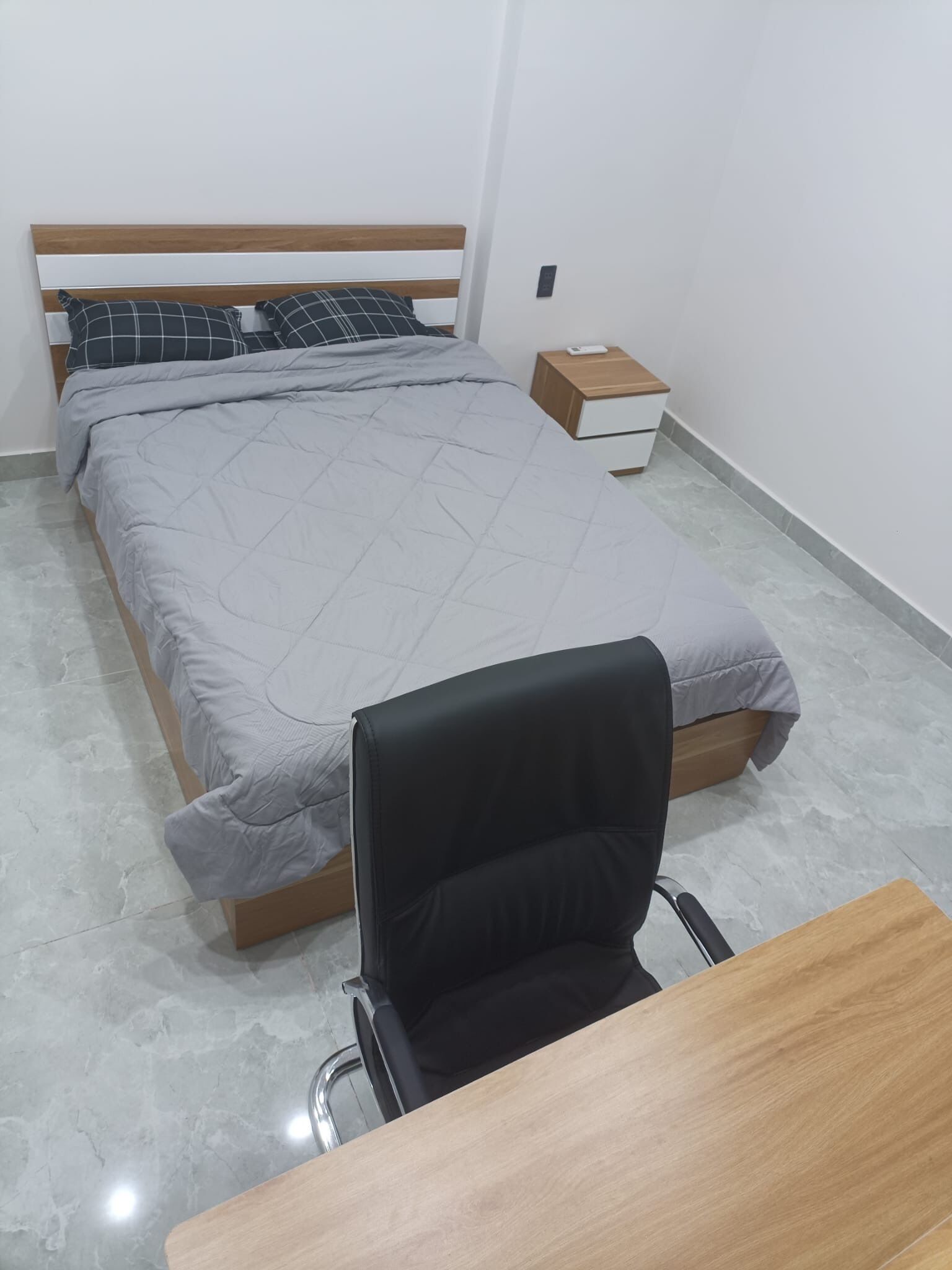 A bedroom with a bed, a nightstand, a desk, and a chair.